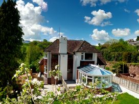 A house with a conservatory and garden surrounded by trees and fields at Harbour Lights in Torquay