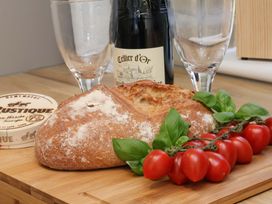 A selection of bread, basil, cherry tomatoes, wine bottle, and glasses