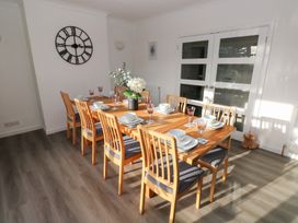 A dining room with a wooden table set for dinner at Westwinds in Tenby