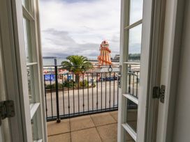 A balcony view overlooking a beach with palm trees at 4 The Beaches Weymouth