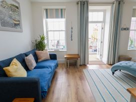A living room with a sofa and window leading to a balcony at 4 The Beaches in Weymouth