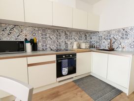A kitchen with cabinets, oven, microwave, kettle, and backsplash at 4 The Beaches in Weymouth
