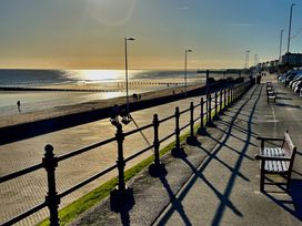 A beach promenade with benches and people walking at Bobbies Retreat, 20 High Street Bridlington