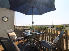 A patio with a table and chairs at Merlin in Malborough