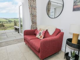 A living room with a red sofa and a view of the outdoors at Orsedd Wen Farmhouse in Betws-Y-Coed
