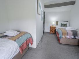 A bedroom with two single beds and a nightstand at Orsedd Wen Farmhouse Betws-Y-Coed