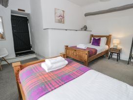 A bedroom with two beds and a door at Orsedd Wen Farmhouse in Betws-Y-Coed