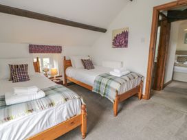 A bedroom with two beds and a lamp at Orsedd Wen Cottage in Betws-Y-Coed