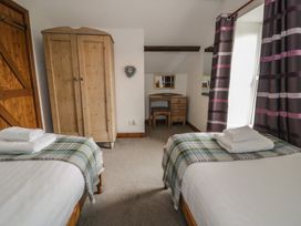 A bedroom with beds and a wardrobe at Orsedd Wen Cottage Betws-Y-Coed