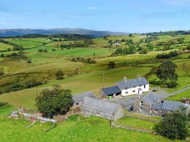 An aerial view of a house and farm buildings surrounded by fields at Orsedd Wen Cottage in Betws-Y-Coed