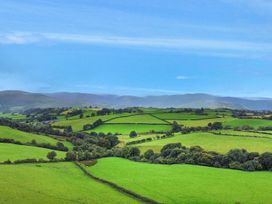 A panoramic view of green fields and hills at Orsedd Wen Cottage in Betws-Y-Coed