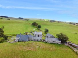 An outdoor view of a house and barn surrounded by fields at Orsedd Wen Cottage Betws-Y-Coed