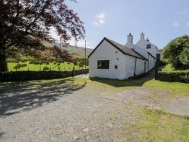 A house with a gravel path and trees at Cwm in Capel Curig