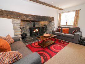 A living room with a wood stove and seating area at Cwm in Capel Curig