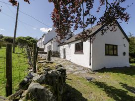 A house with a stone pathway and fence at Cwm in Capel Curig