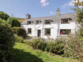 A house with windows and door surrounded by grass and bushes at Cwm in Capel Curig