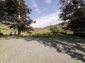 A view of a gravel area with trees and mountains at Cwm in Capel Curig