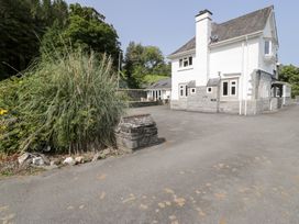 An outdoor view of a house with a stone wall and grass at Pengwern Bach Llanrwst