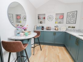 A kitchen with a table and bar stools at Pengwern Bach Llanrwst