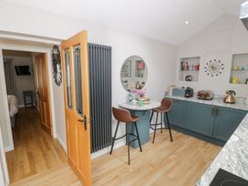 A kitchen with a table and stools at Pengwern Bach in Llanrwst
