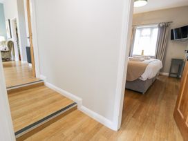 A hallway leading to a bedroom with a bed and television at Pengwern Bach Llanrwst