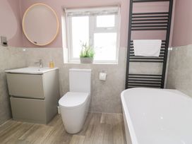 A bathroom with a bathtub, toilet, sink, and towel rack at Pengwern Bach in Llanrwst