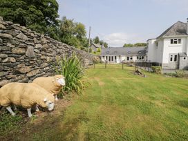 A garden with sheep sculptures and a stone wall at Pengwern Bach Llanrwst