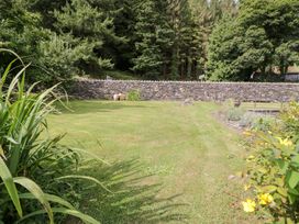 A garden with grass and a stone wall at Pengwern Bach in Llanrwst