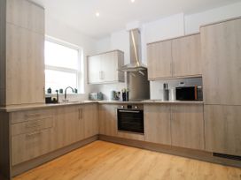 A kitchen with wood cabinets a window a stainless steel oven microwave and countertop appliances at Sea Nest in Torquay