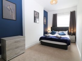 A bedroom with a double bed two bedside tables lamps a chest of drawers and framed pictures on the walls at Sea Nest in Torquay