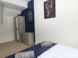 A bedroom with a bed with towels on it a wardrobe a chest of drawers and two framed pictures on the wall at Sea Nest in Torquay