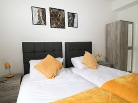 A bedroom with two single beds with yellow pillows and blankets two bedside tables with lamps and a wooden wardrobe at Sea Nest in Torquay