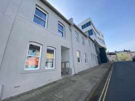 A street view showing a row of white and gray buildings with multiple windows and a For Sale sign in one window at Sea Nest in Torquay