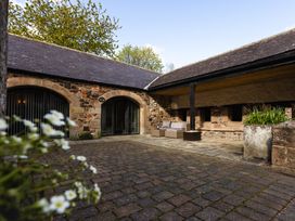 An outdoor area with stone walls and lounge furniture at Fern Cottage in Akeld near Wooler