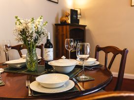 A dining table set with plates, glasses, and a wine bottle at Fern Cottage in Akeld near Wooler