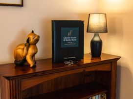 A wooden cabinet with a cat statue and guest information booklet at Cheviot Manor in Wooler