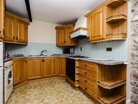 A kitchen with wooden cabinets and appliances at Fern Cottage Akeld near Wooler