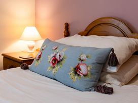 A bed with a decorative pillow and lamp at Fern Cottage Akeld near Wooler