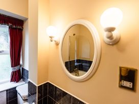 A bathroom with a mirror, toilet and light fixtures at Fern Cottage in Akeld near Wooler
