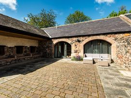 An outdoor seating area with stone walls and paved surface at Lupin Cottage near Wooler