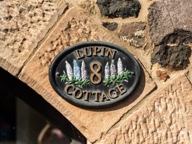 A nameplate for Lupin Cottage 8 on a stone wall at Lupin Cottage in Akeld near Wooler