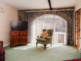 A living room with a television and an armchair at Lupin Cottage near Wooler