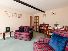 A living room with plaid sofas and a dining table at Lupin Cottage in Akeld near Wooler