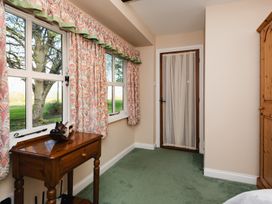 A bedroom with windows and green carpet at Lupin Cottage in Akeld near Wooler