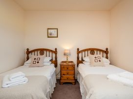 A bedroom with two beds and a nightstand at Bramble Cottage in Akeld near Wooler