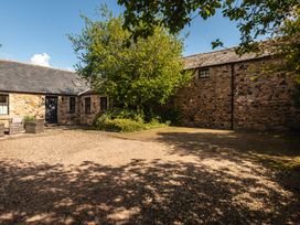 An outdoor area with a stone building and a gravel driveway at Bramble Cottage in Akeld near Wooler