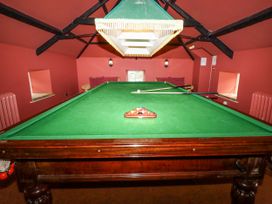 A snooker table with balls and a cue stick in a snooker room at Tile Rouge in Wooler