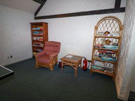 A snug with an armchair, bookshelves, coffee table, and board games at Tile Rouge in Wooler