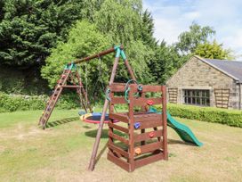 A garden with a swing set and slide at Tile Rouge in Wooler