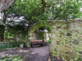 A garden with a stone archway and a bench at Catkin Cottage Akeld near Wooler